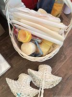 Basket with taper candles, jar candle, pillar candle and small wicker bells visible