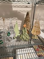 Shelf with six assorted tabletop Christmas trees in various materials and colors