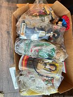 Box containing multiple bagged souvenir dolls showing variety of national costumes