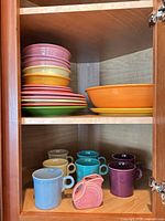 Cabinet shelf showing stacks of plates, serving bowl, mugs and creamer