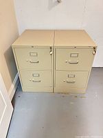 Front view of two beige metal two-drawer filing cabinets side by side