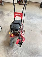Front angled view of Homelite gas lawn edger showing engine, handle, wheels, and blade guard