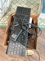 Two black wired keyboards and cables in box