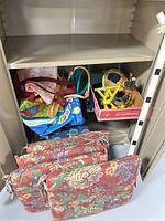 Cabinet showing five floral cushions, tote bags and box with sprinklers