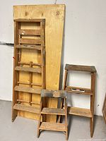 Straight ladder, folding step stool ladder and plywood panel shown together