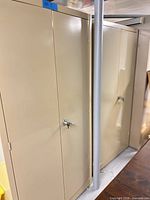 Two tall beige metal cabinets side by side with locking door handles