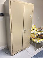 Front view of beige metal storage cabinet with double doors and keyed handle