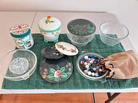 All items laid out on green towel showing glass bowls, ceramic jar, coasters, marbles pouch and jar