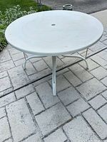 Full view of round white patio table on stone patio