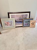 Four framed prints leaning against wall showing relative sizes and frame finishes