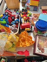 Overview of mixed toddler toys including Fisher-Price grill pieces, stacking blocks, Play-Doh molds, toy vehicles, and boxed books
