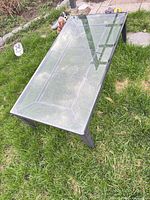 angled view of rectangular glass top metal patio coffee table on grass