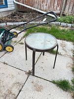 Full view of round metal side table with textured glass top on patio