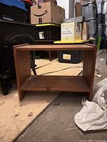 Front view of small brown stained wooden side table showing two tiers and overall wear