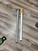 Two metal table legs, one wrapped, showing round mounting flanges and white finish