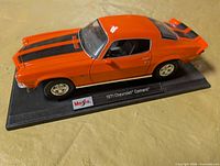 Left front view of orange 1:18 Camaro on display base