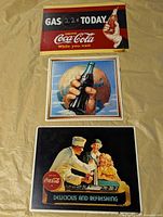 All three Coca-Cola metal signs laid out on surface