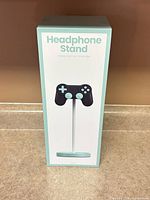 Front of boxed mint teal video game controller headphone stand