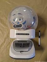 Front view showing full toy with dome, base, pen for scale