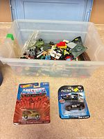Overall lot with storage tub of loose toys and two packaged cars displayed