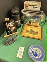 Group shot displaying toaster with box, coffee grinder, framed print, lacquer panel on easel, figurine, plate