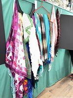 Group of hanging scarves showing variety of colors, patterns and fringe