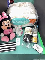 Group shot of all items including Snoogle pillow, Minnie plush, pacifiers, scarf, wallet, card holder