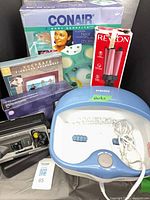 Group shot showing Conair box, Revlon styler, Keepsafe frame, Motorola charger in case, HoMedics foot bath