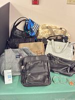 Group shot of all handbags, scarf, bangles and bead container on table