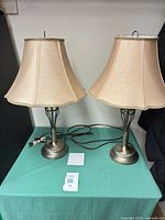 Front view of both matching lamps showing metal bases, fabric shades, cords