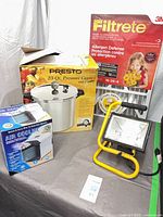 Group shot of all four items: Presto canner box, Filtrete filter, air cooler box, work light on stand
