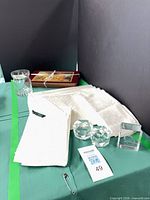 Stack of Ralph Lauren napkins, glass tumbler, two faceted tealight holders and glass block on table