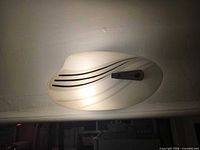 Front view of illuminated wall sconce showing curved glass shade and black stripes