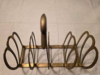 Top view of brass swan rack showing four slots and central handle