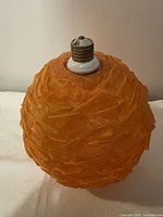 Exterior view of orange mesh ribbon globe shade with socket fitting