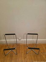 Two identical metal stands against wall on wooden floor