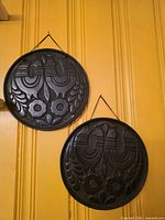 Both metal discs hanging on wall showing size and finish