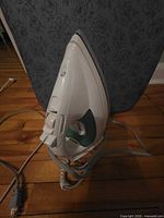 Steam iron resting against blue-covered ironing board