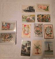 Group shot showing 11 assorted postcards, plastic sleeve with extras, variety of themes
