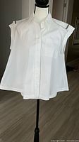 Front view of white sleeveless button-up blouse on mannequin