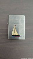 Closed lighter front showing sailboat enamel on brushed chrome body