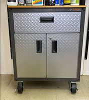 Front view showing diamond-plate drawer and doors, recessed handles, casters, and wood top