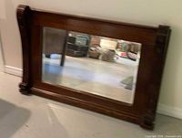 full view of large rectangular wood mirror leaning against wall