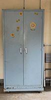 Front view of closed cabinet showing light blue exterior, double doors, handles, floral decals, and casters