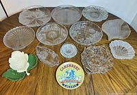 Overview of all 14 glass and ceramic serving pieces on table