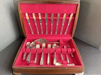 Open flatware case showing knives, forks, spoons, serving pieces