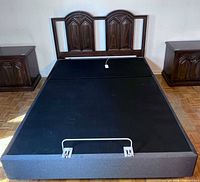 Overall view of queen adjustable base with wood headboard, metal retainer bar visible