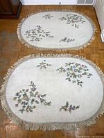 Both oval rugs on floor showing full design and fringe