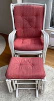 Front view of white wicker rattan glider armchair with matching ottoman, pink cushions visible