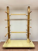 Full view of wooden drying rack showing frame, arms and yellow wheeled base